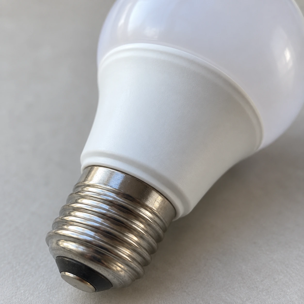 Gros plan sur le culot E27 fileté et le collier blanc vierge de l'ampoule radar
