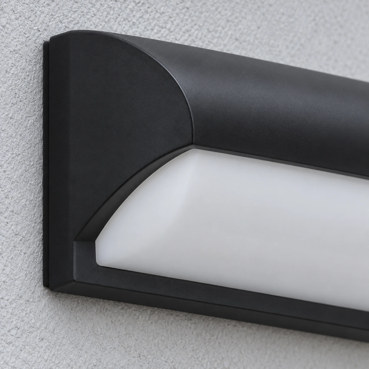 Le bout gauche de l'applique éteinte, capot noir mat et platine de fixation en tranche