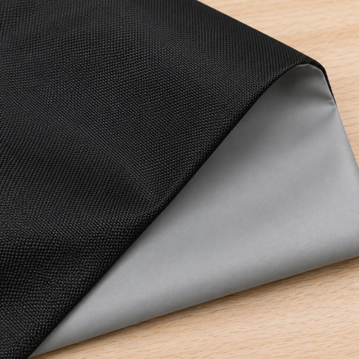 Intérieur de la housse retournée, doublure PVC gris clair uniforme sur l'envers du tissu Oxford noir