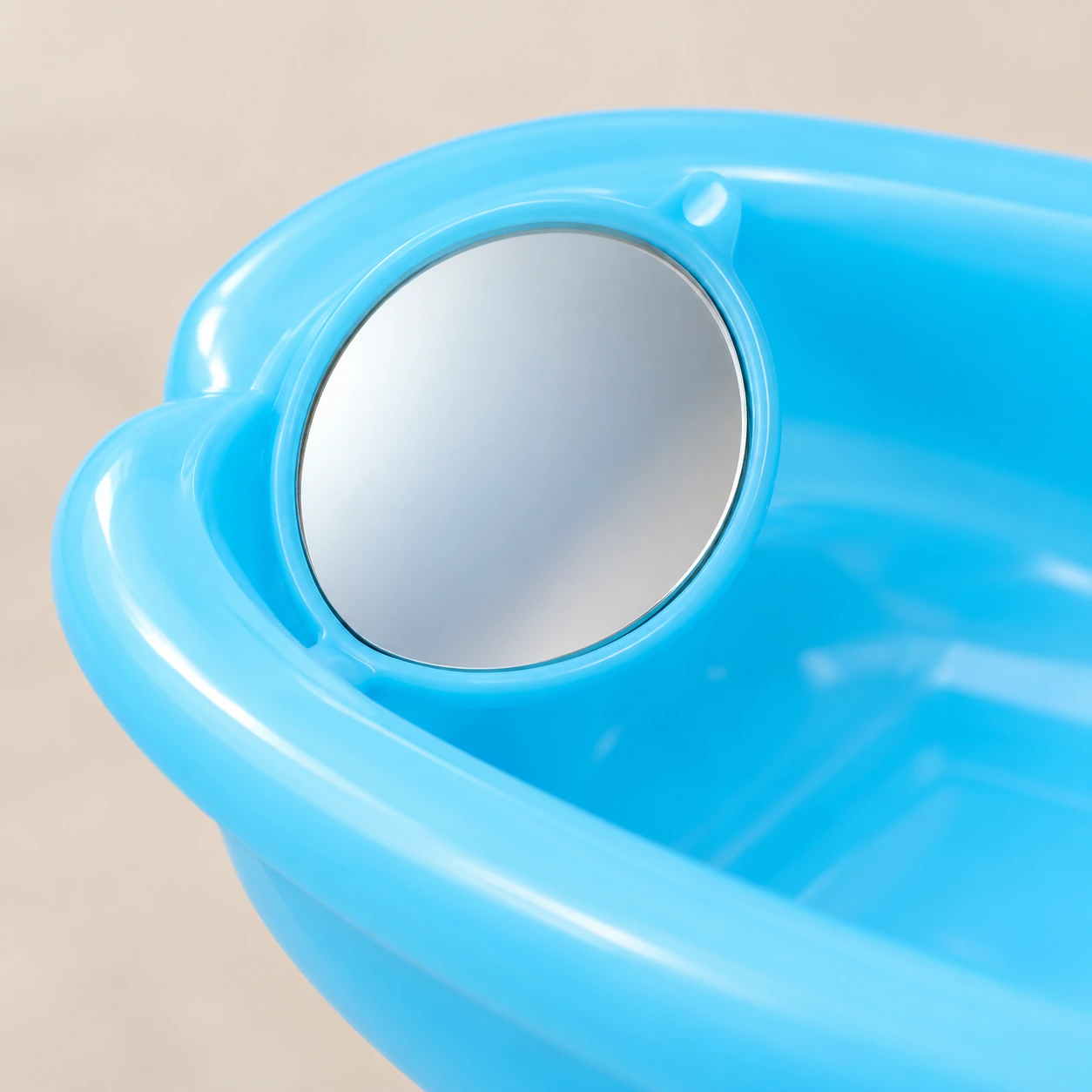 Le miroir rond du bol de bain, logé en biais dans sa collerette bleue
