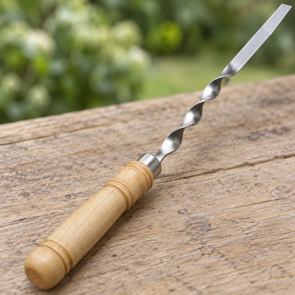 Gros plan sur la jonction d'une brochette : lame plate, tronçon torsadé, virole et manche en bois blond