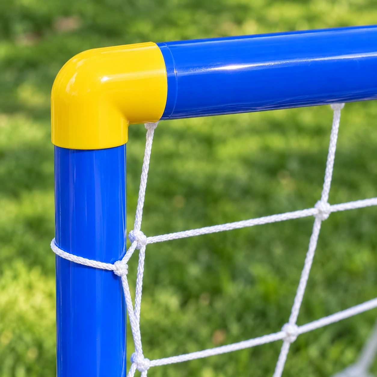 Gros plan sur un coin du cadre : le coude jaune entre deux tubes bleus, lacé au filet