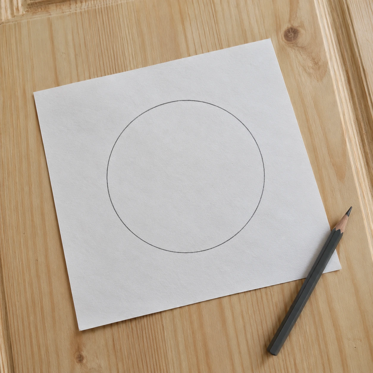 Patron de découpe en papier posé sur un vantail, cercle tracé au crayon avant la découpe