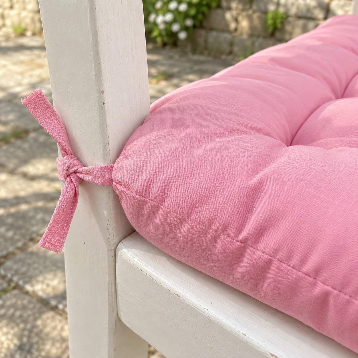 Ruban de tissu plat cousu dans l'angle arrière du coussin rose, noué autour du montant de la chaise