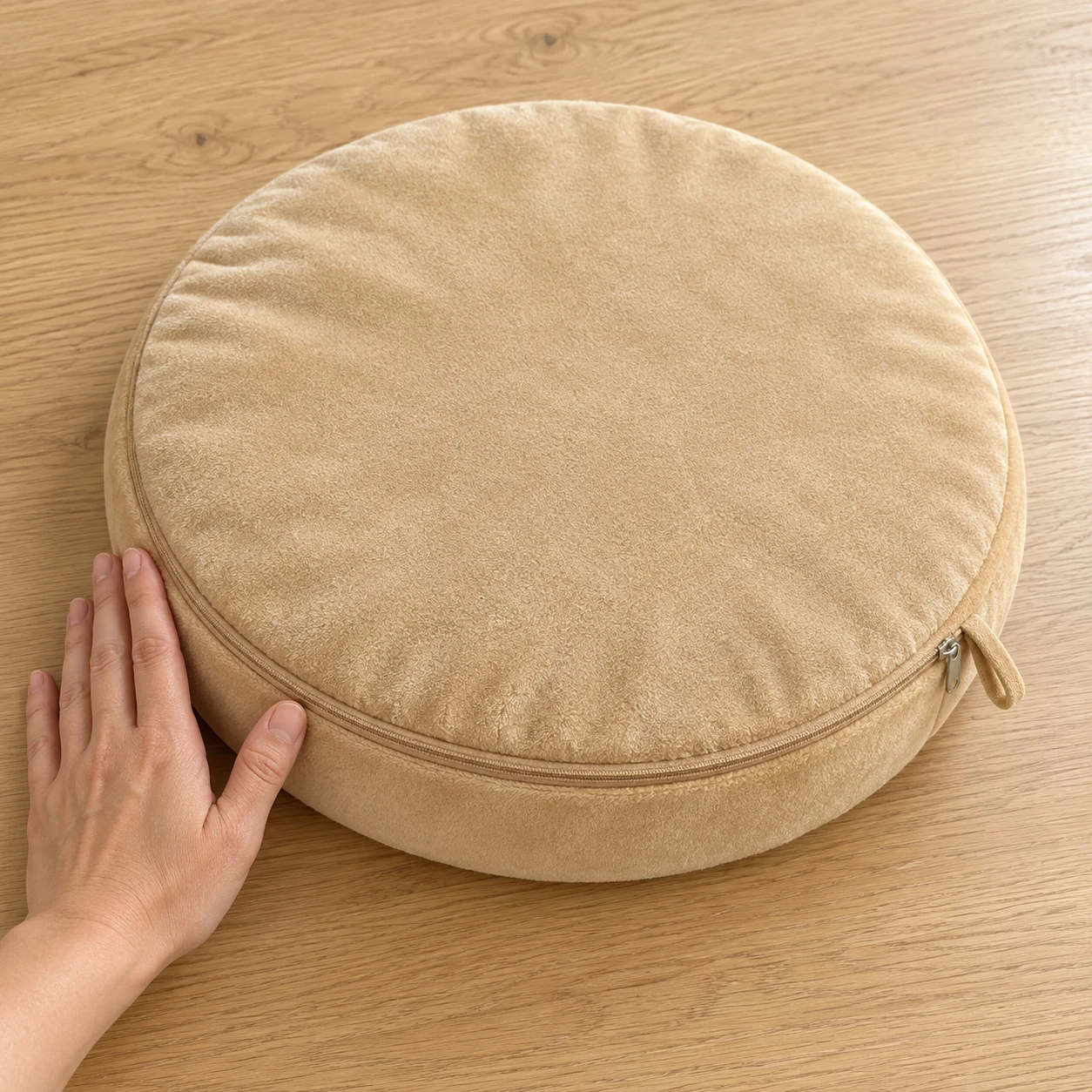 Dessous uni beige du coussinet, fermeture à glissière et patte de suspension, avec une main pour l'échelle