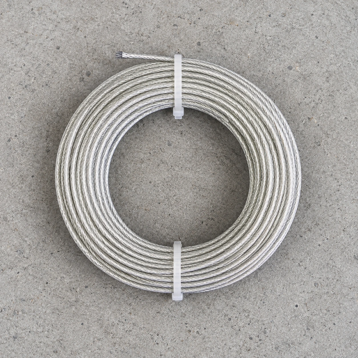 Contenu du colis vu de dessus : une bobine de fil d'acier de 15 m avec ses deux colliers blancs, sur fond blanc
