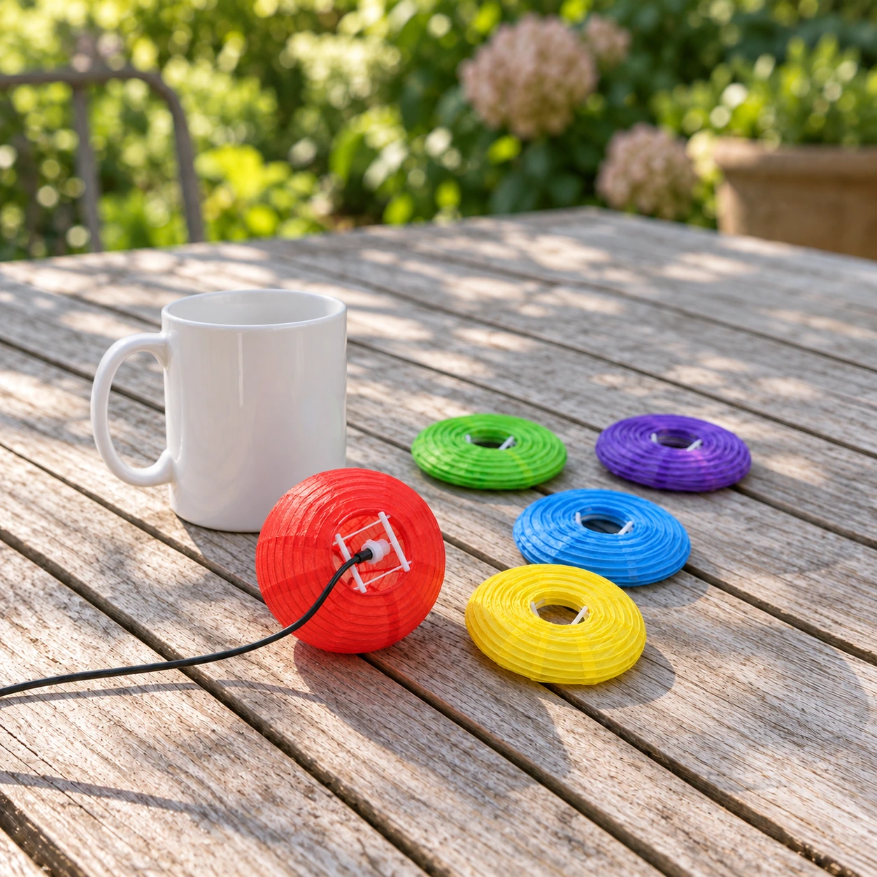 Lanterne rouge ouverte sur son clip à côté d'une tasse, lanternes encore à plat sur la table