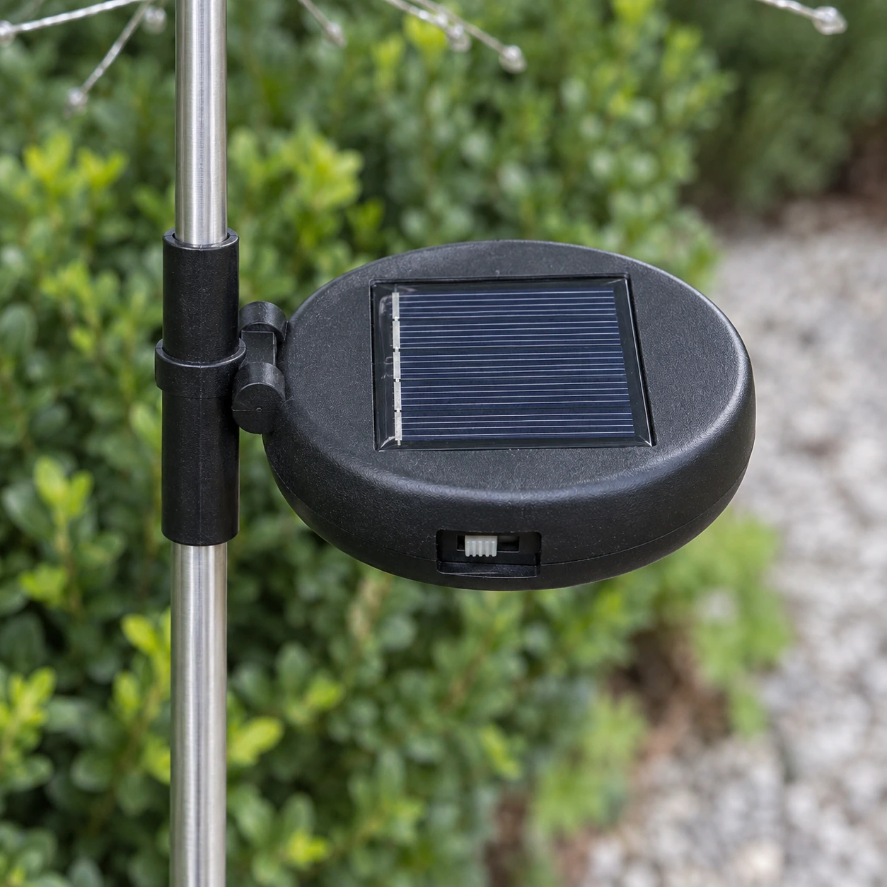 Gros plan du boîtier solaire noir monté sur la tige, panneau photovoltaïque et interrupteur ON OFF visibles