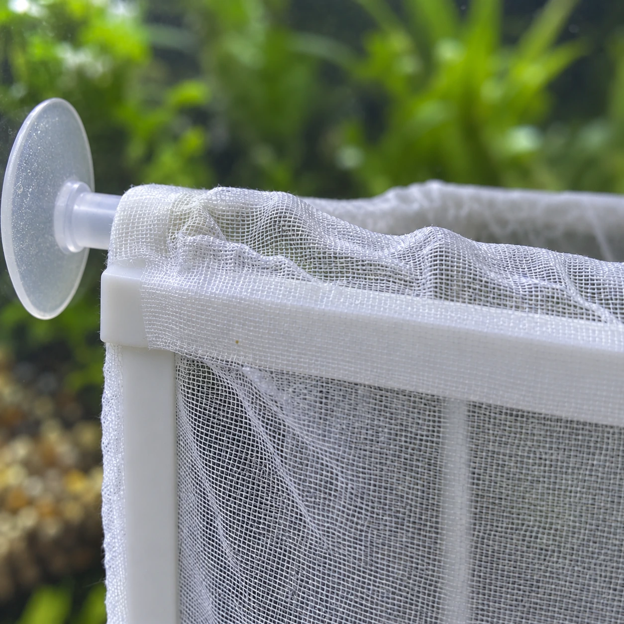 Vue de face du panier monté : le cadre blanc, la maille glissée dessus sur les quatre parois et le fond, deux ventouses sur le bord