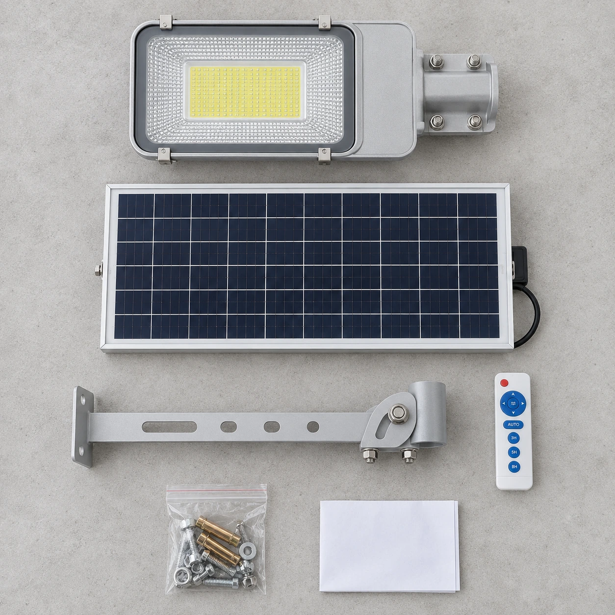 Les six pièces du colis alignées : luminaire, panneau, support, télécommande, visserie et notice