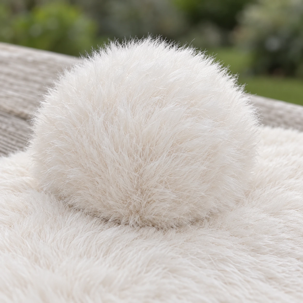 Le pompon rond cousu sur la polaire, vu de très près au bord du tapis
