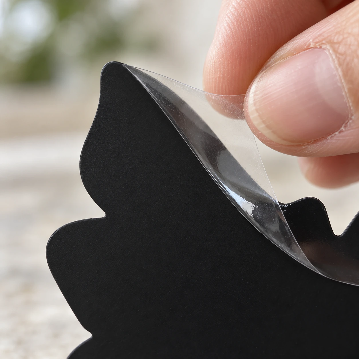 Gros plan sur la pellicule de protection translucide qu'on retire du bord d'une plaque collante noire tournesol