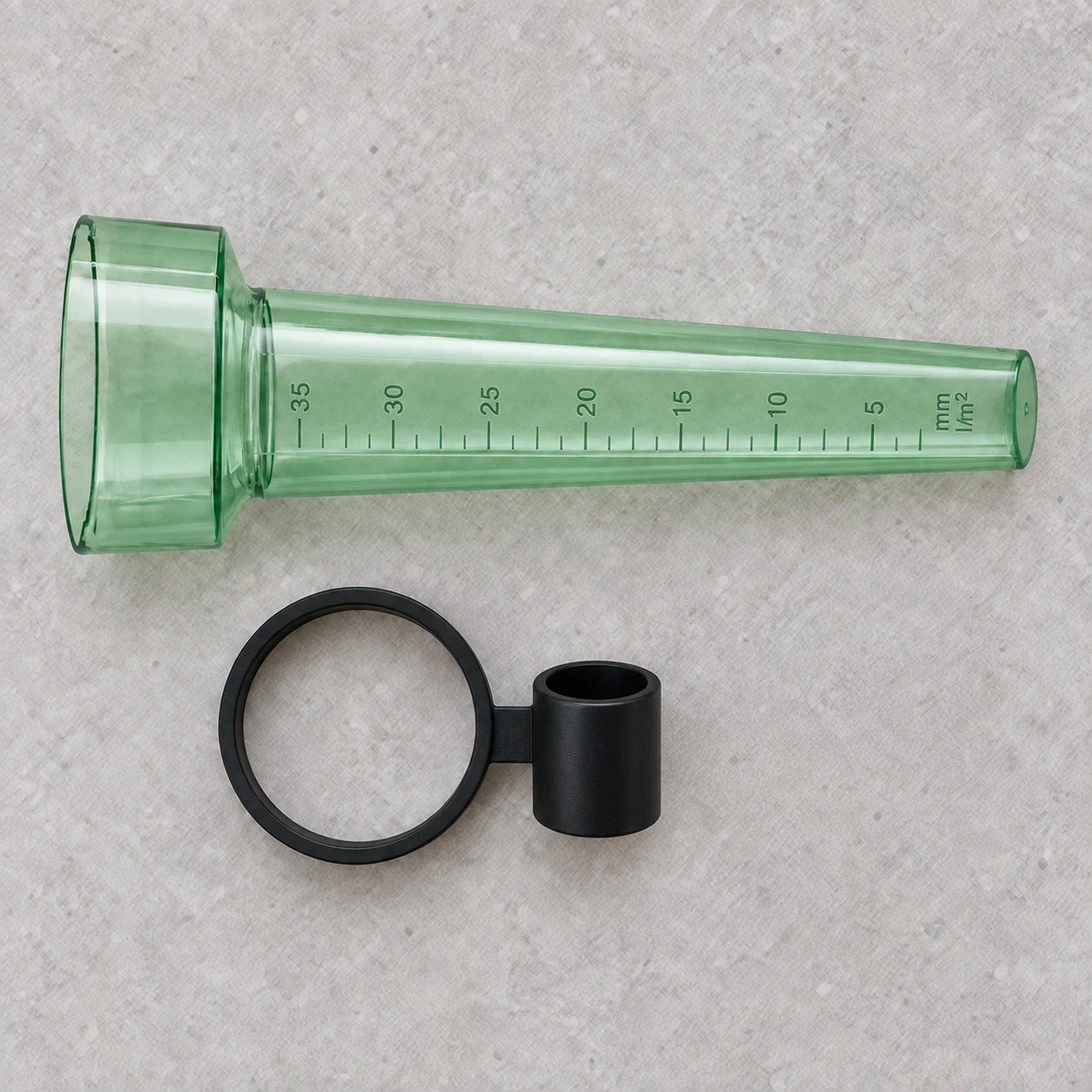 Contenu du colis du pluviomètre : le tube gradué vert clair et la bague de fixation noire, posés à plat