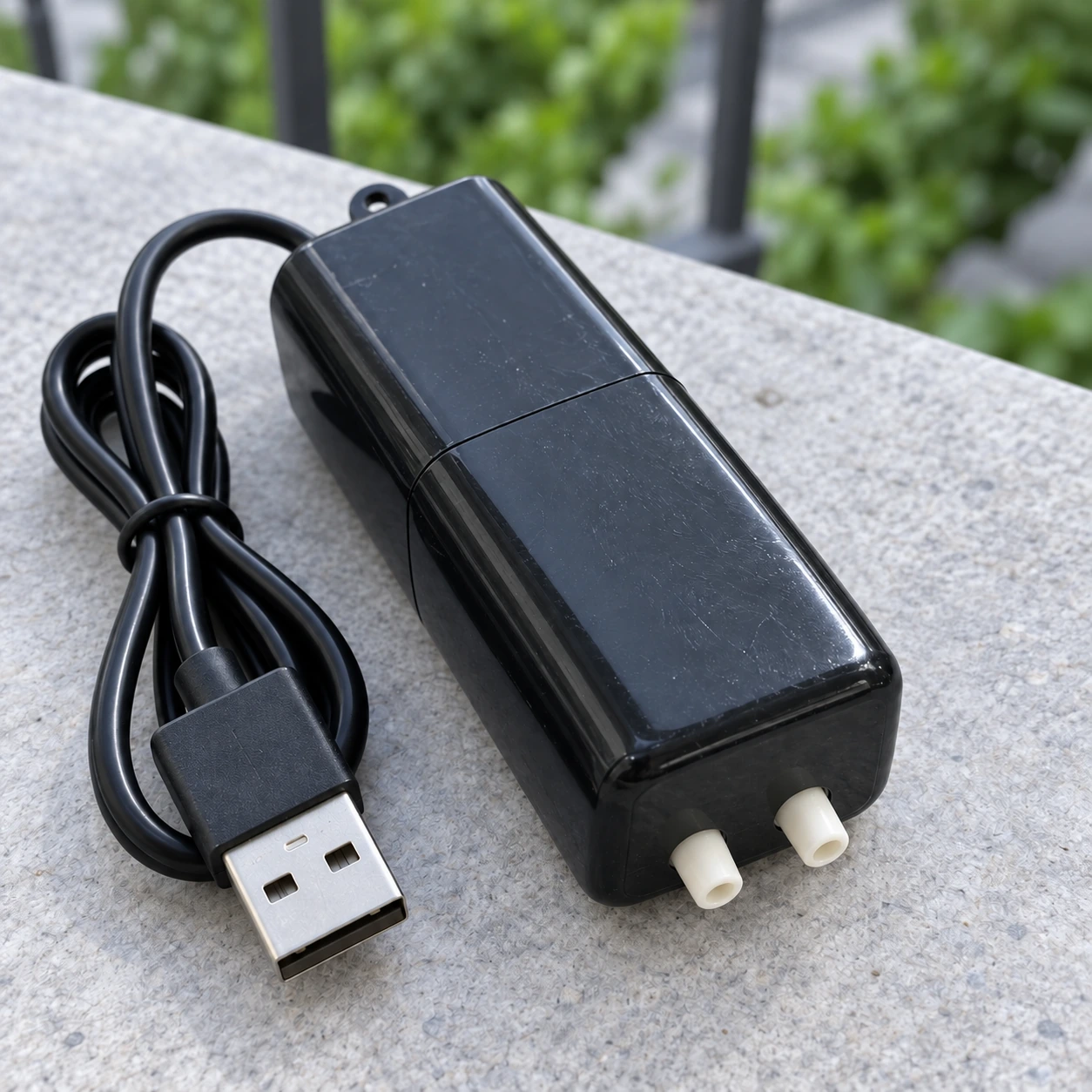 Dessous de la pompe : deux embouts d'air blanc cassé côte à côte, à côté de la prise USB du câble
