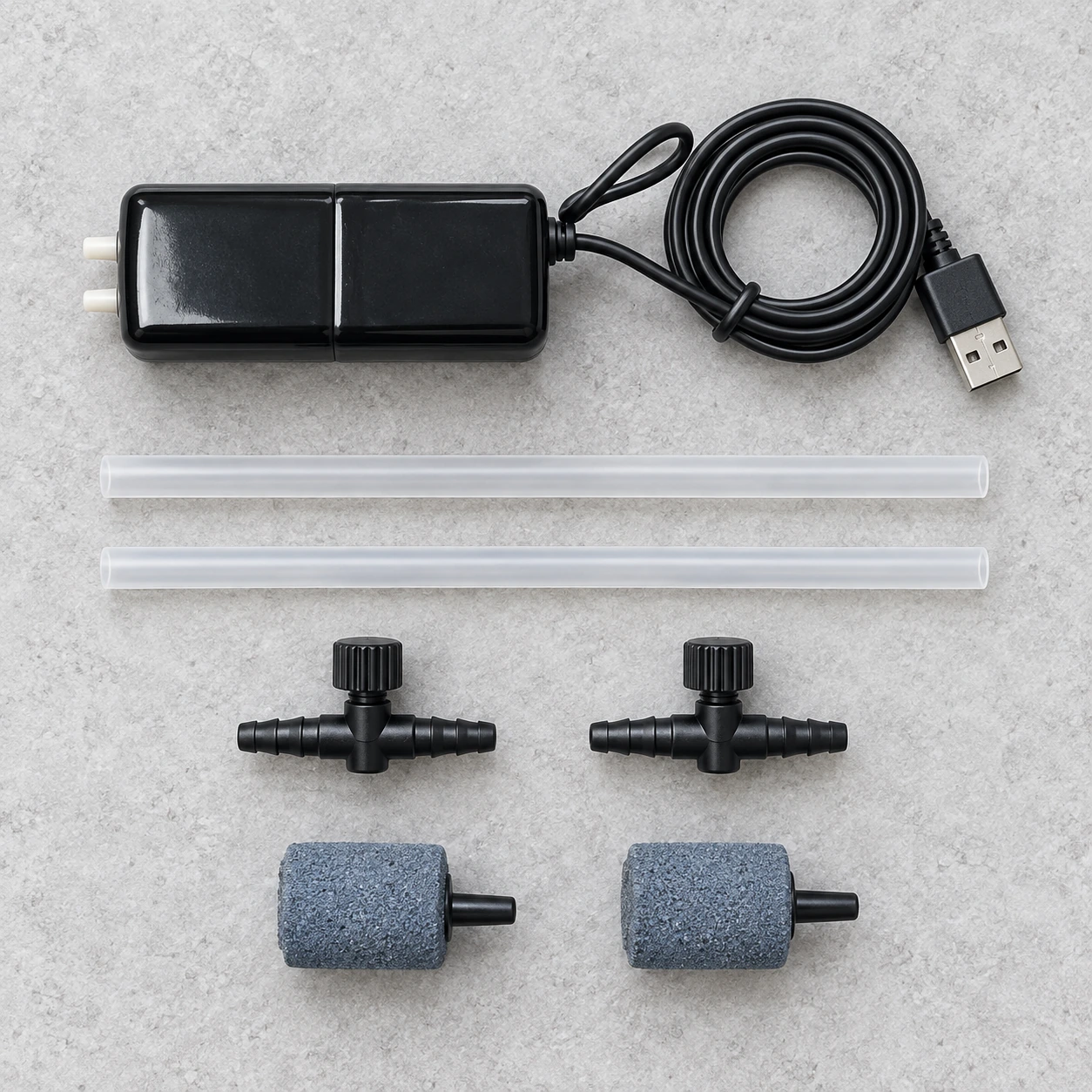 Contenu du kit posé à plat : pompe, câble USB, deux tuyaux, deux régulateurs et deux pierres diffusantes
