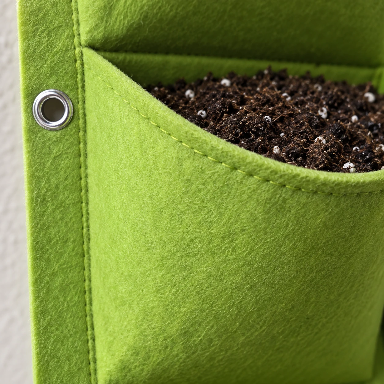 Gros plan sur la couture de renfort et l'œillet d'un panneau de feutre vert clair