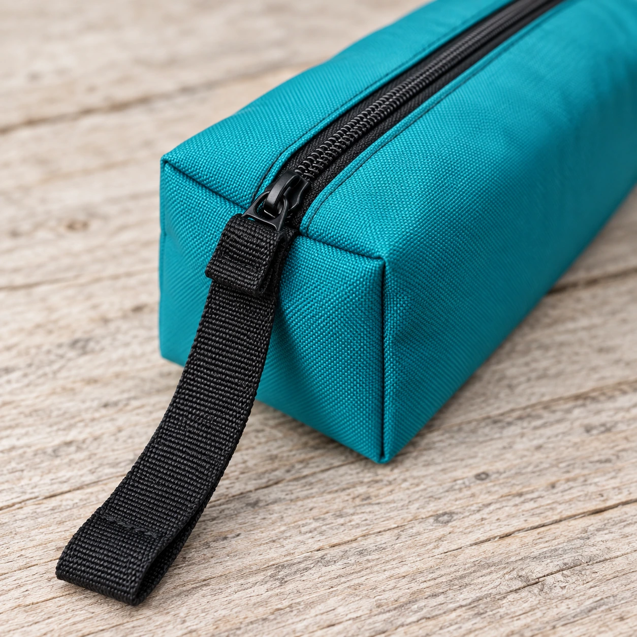 Détail de la fermeture à glissière et de la sangle plate cousue à l'extrémité de la pochette