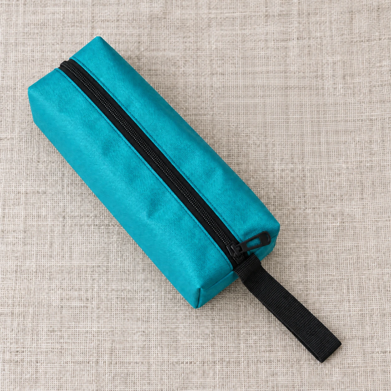 Contenu du colis : une pochette turquoise et sa sangle posées à plat sur une toile claire