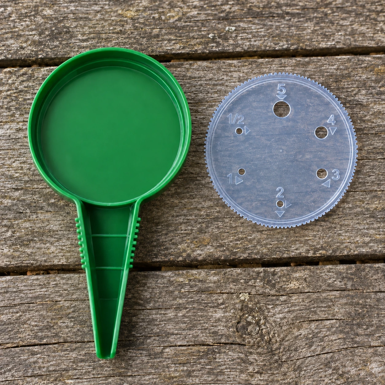 Le disque transparent retiré du semoir, posé à côté du corps vert sur une table en bois